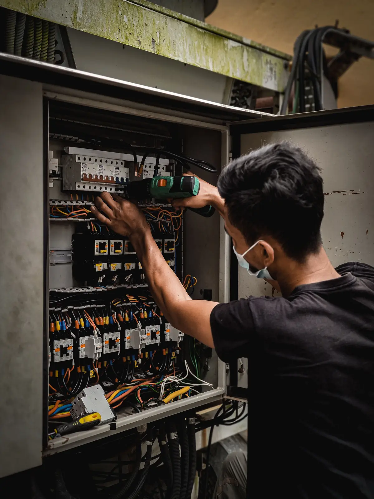 An electrician working inside a large distribution board, for panel upgrade in Barrie